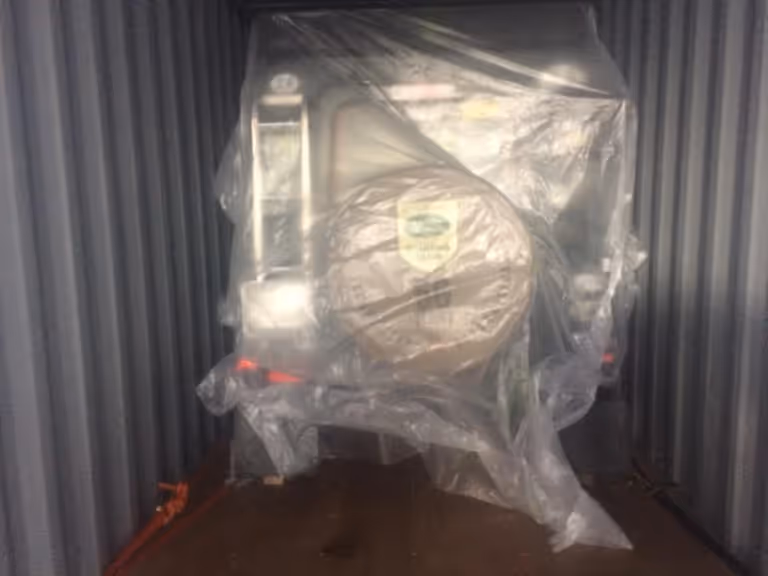 Vehicle wrapped in protective plastic inside a shipping container